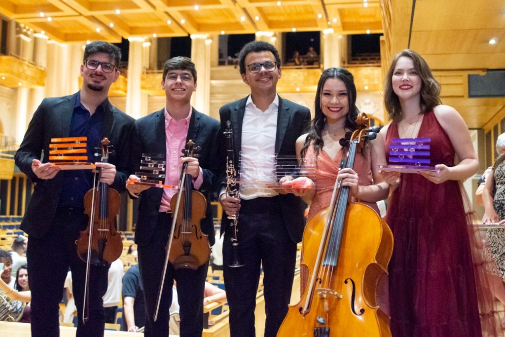 #ParaTodosVerem: Foto registrada na Sala São Paulo, em destaque temos 5 pessoas que estão segurando instrumentos musicais e o troféu do prêmio.